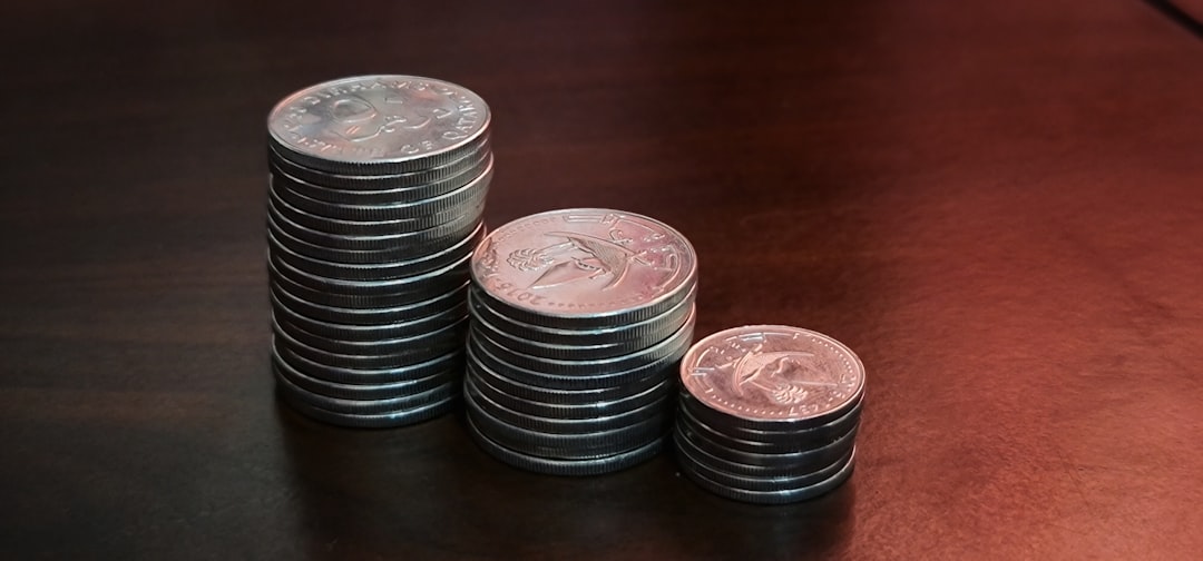 Three ascending stacks of silver coins on a wooden table