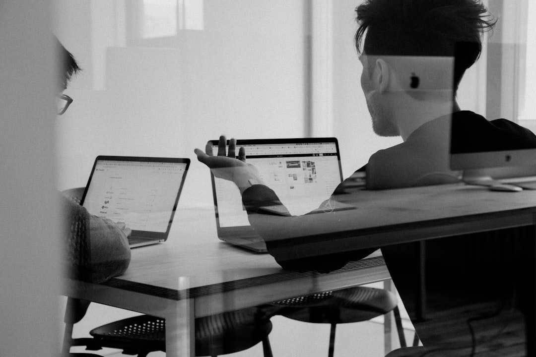 Black-and-white double exposure of people working on laptops